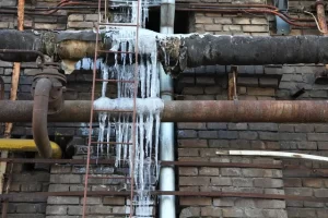 A pipe that has been frozen and is hanging from the side of a building.